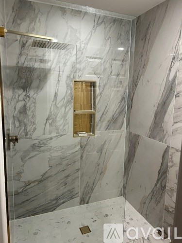 A bathroom with a marble wall and a glass shower door.