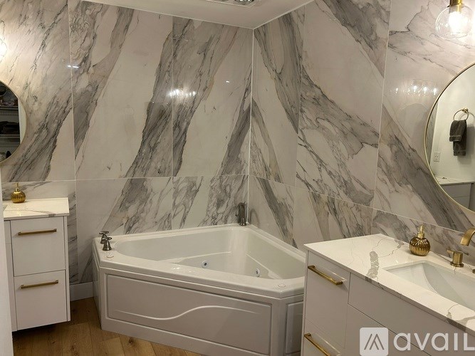 A bathroom with marble walls and a white bathtub.