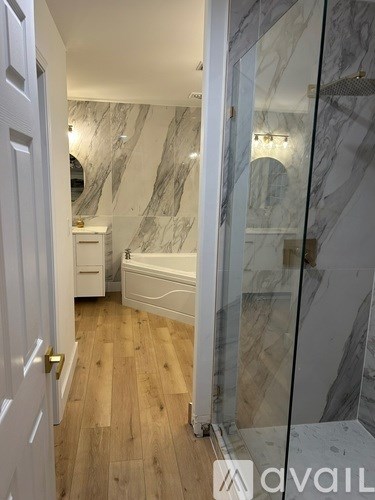 A bathroom with marble walls and a wooden floor.
