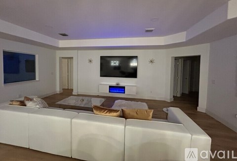 A modern living room with a white sofa and a television mounted on the wall.