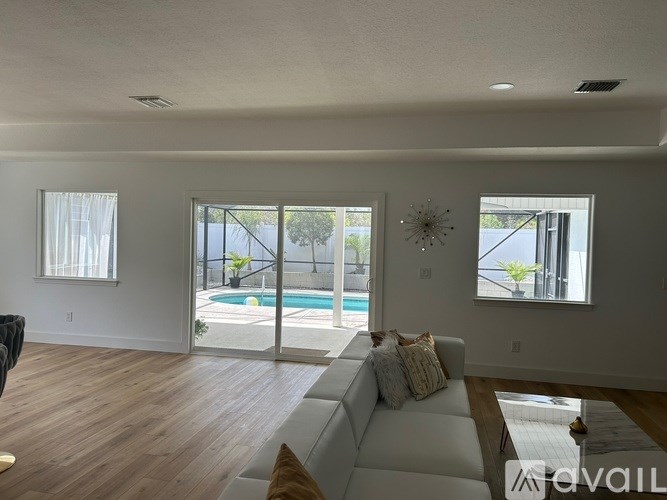 A living room with a pool outside the window.