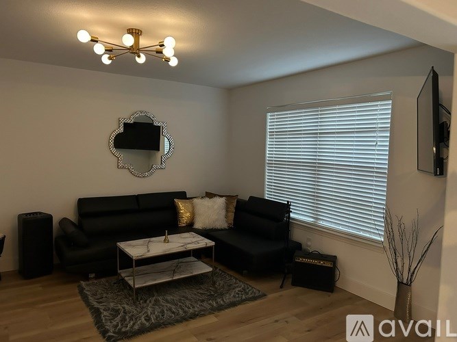 A living room with a black couch, a coffee table, and a mirror on the wall.