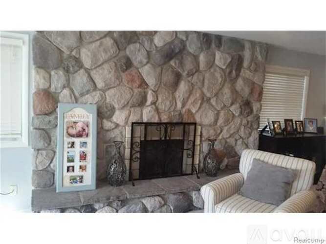 A stone fireplace with a framed menu on the mantle and a striped couch in front.
