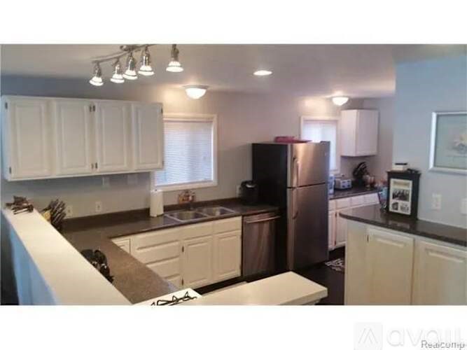 A kitchen with white cabinets and a black refrigerator.