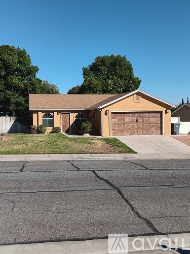 A house with a brown garage door is surrounded by a driveway and trees.