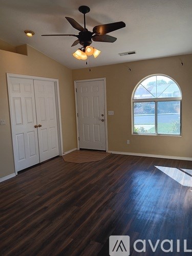 A room with a ceiling fan and wooden flooring.