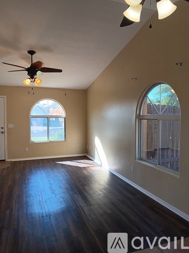A room with a ceiling fan and wooden floors.