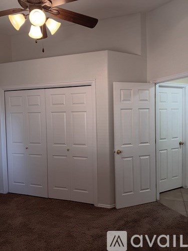 A room with a ceiling fan and three white doors.