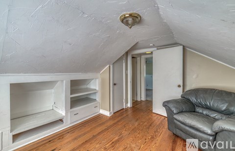 A living room with a black leather couch and a wooden floor.