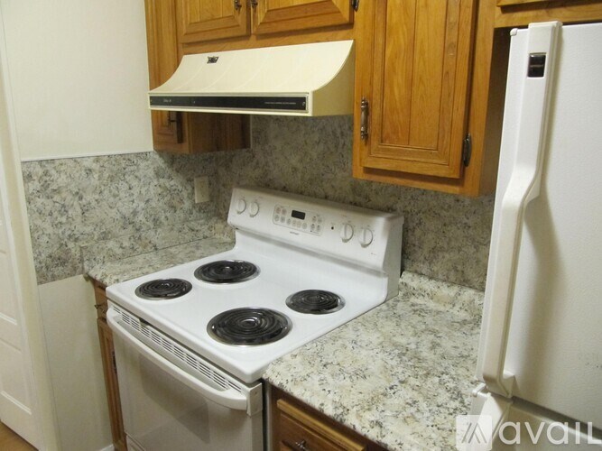 A white stove top oven with four burners and a white refrigerator in a kitchen.