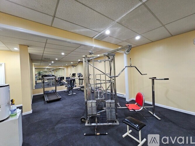 A gym with a variety of equipment including a weight bench, a leg press machine, and a squat rack.
