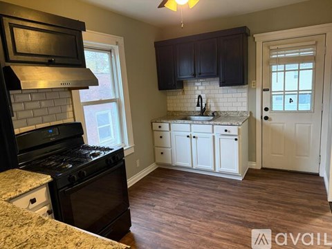 A kitchen with dark wood cabinets and a black stove top oven.