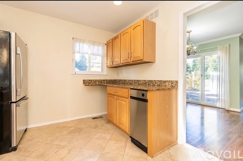 A kitchen with wooden cabinets and a black fridge.