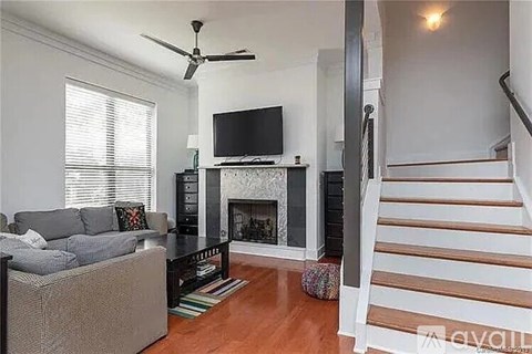 A living room with a grey couch and a television on a black stand.