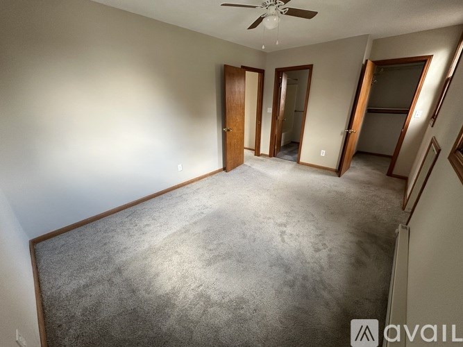 A spacious room with a carpeted floor and a ceiling fan.