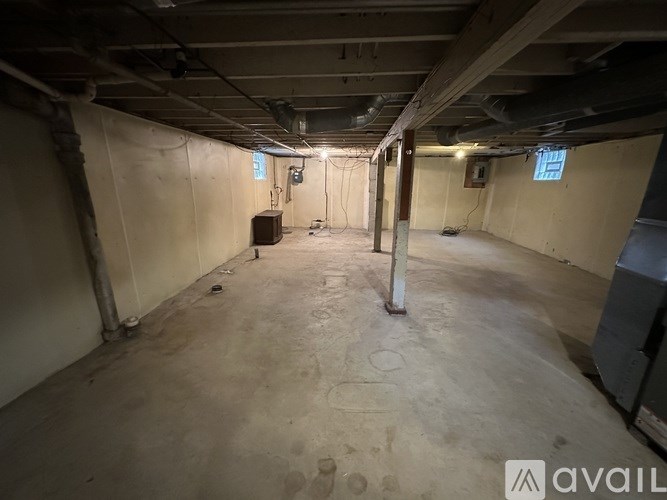 A spacious basement with concrete floors and exposed ceiling beams.