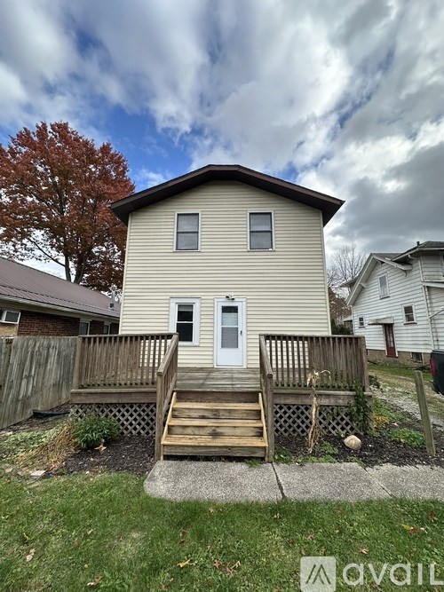 A house with a white door and a brown roof with a wooden fence in front.