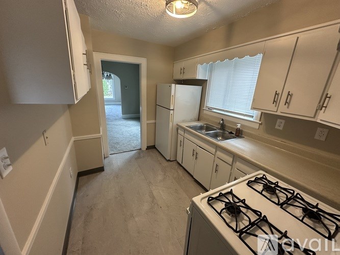 A kitchen with a white stove top oven and white cabinets.