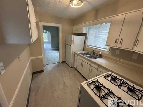 A kitchen with a white stove top oven and white cabinets.