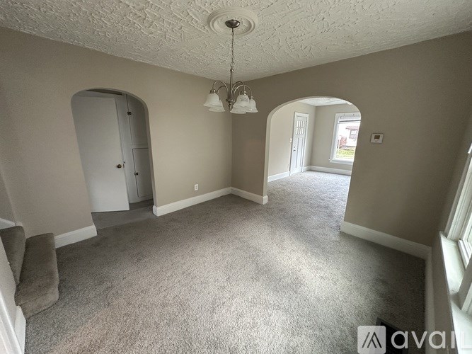 A room with a carpeted floor and a chandelier hanging from the ceiling.