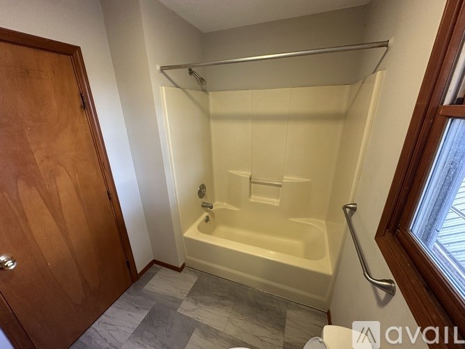 A bathroom with a tub, shower, and a wooden door.