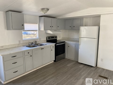 A kitchen with a white fridge, sink, and cabinets.