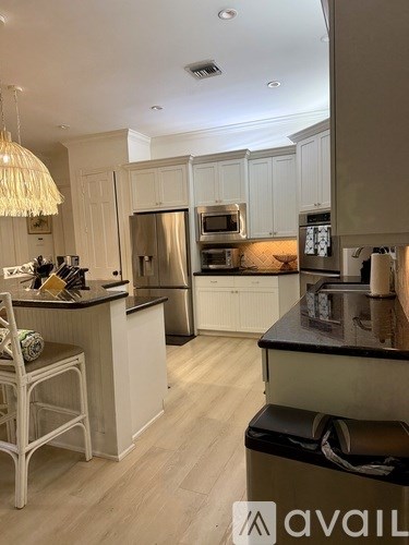 A kitchen with a black countertop and stainless steel appliances.