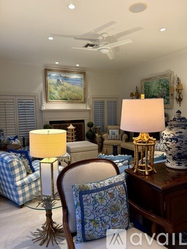A living room with a blue and white checkered couch, a wooden chair, a lamp, and a painting on the wall.