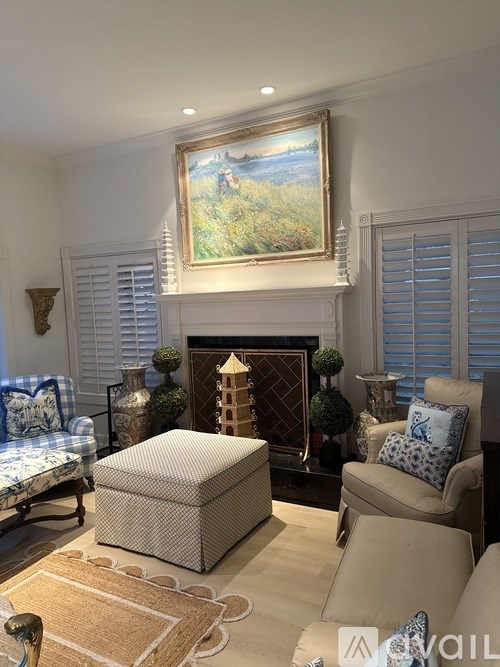A living room with a large painting above a fireplace and a couch with blue and white pillows.