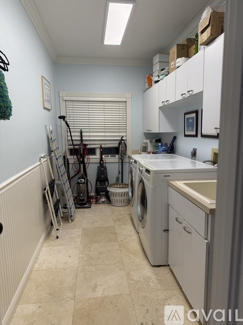 A laundry room with a washer and dryer, a basket, and a mop.