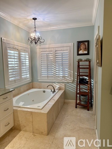 A bathroom with a tub, a chandelier, and a painting on the wall.