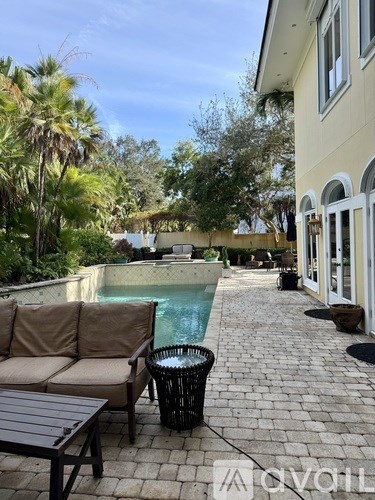 A patio with a couch, table, and a pool.