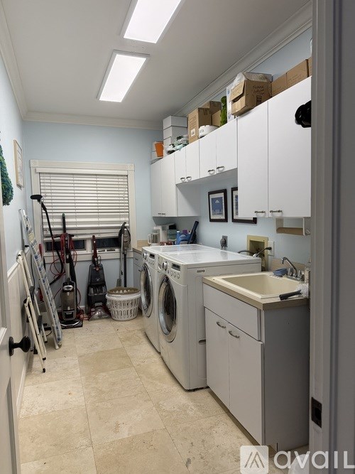 A laundry room with a washer and dryer, a sink, and a window with blinds.