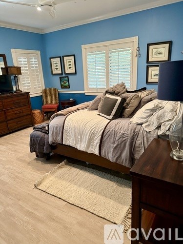A bedroom with a bed, dresser, and window with blinds.