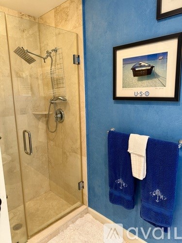A shower with a glass door and a white towel hanging on the wall.