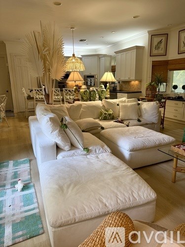 A living room with white furniture and a large window.