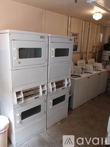 A row of white ovens and microwaves are stacked in a room.
