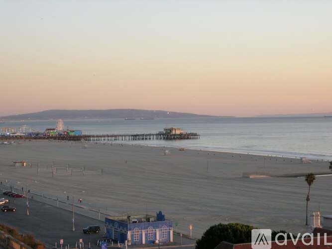 A beach scene with a pier and buildings in the distance.