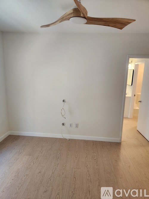 A room with a ceiling fan and wooden flooring.