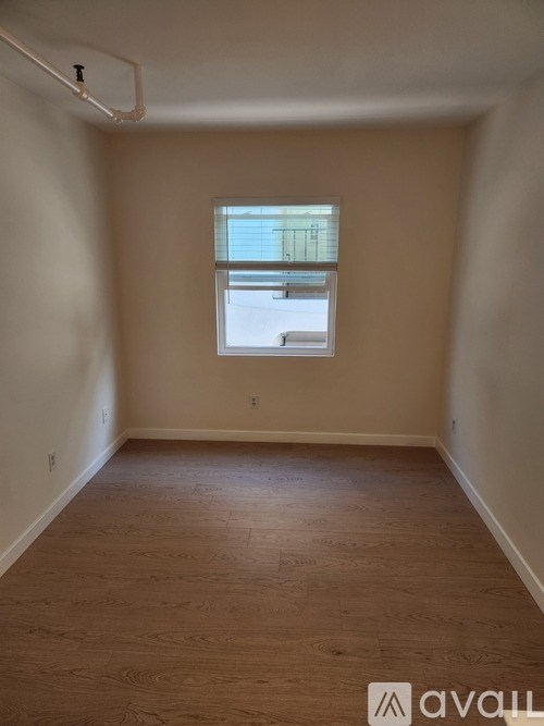 A room with a window and wooden flooring.