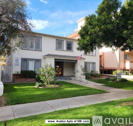 A white two-story apartment building with a flag on the front.