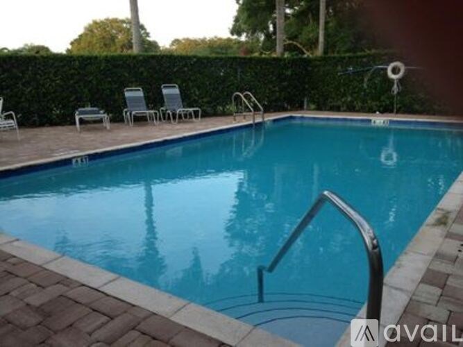 A pool with a ladder and chairs around it.