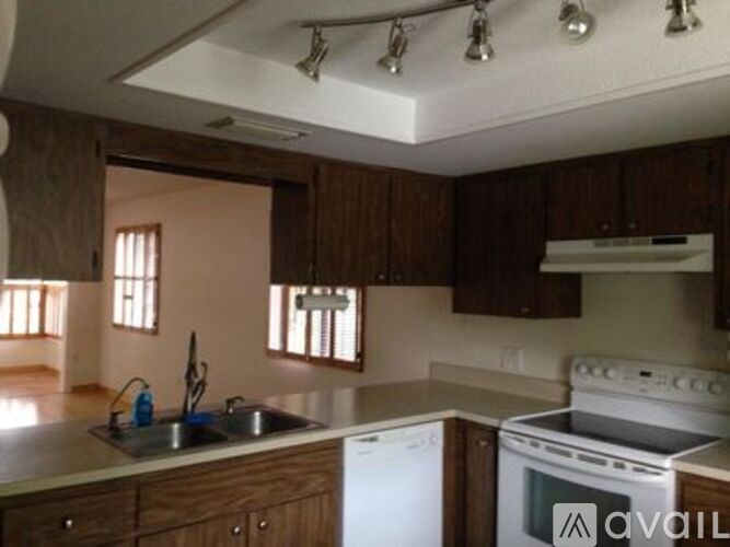 A kitchen with wooden cabinets and a white stove top oven.