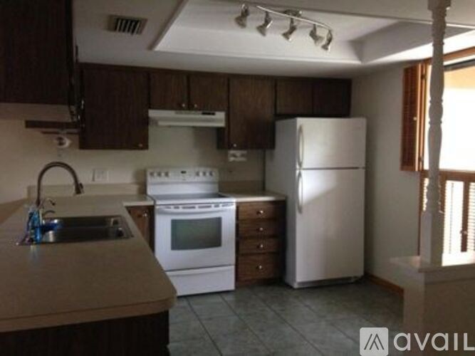 A kitchen with white appliances and wooden cabinets.