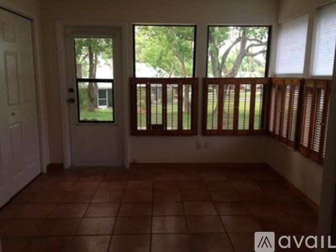 A room with a tiled floor and a view of a tree through the window.