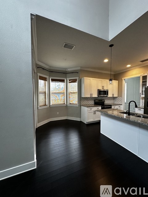 A kitchen with white cabinets and black countertops.