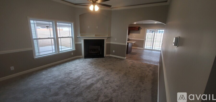 A spacious living room with a fireplace and a ceiling fan.