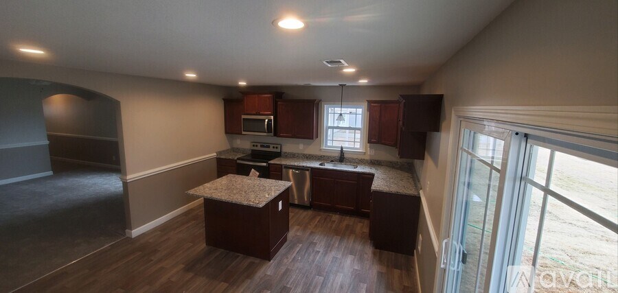 A kitchen with dark wood floors and a large island in the middle.