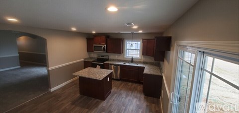 A kitchen with dark wood floors and a large island in the middle.