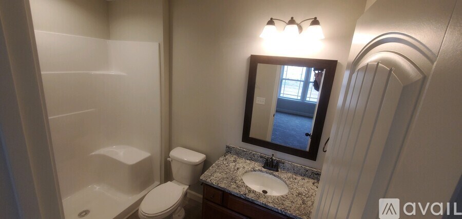 A bathroom with a toilet, sink and mirror.